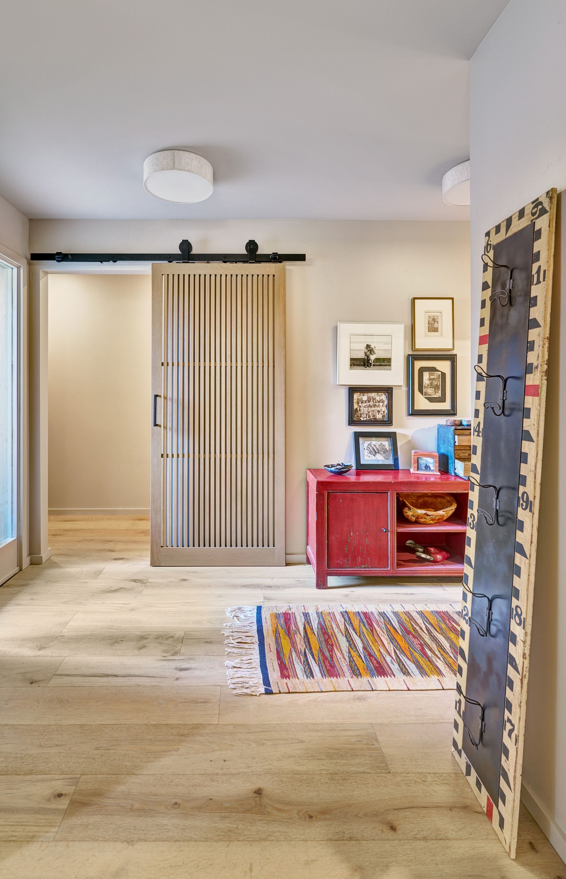 Bedroom with a barn door, light wood floors, and a red dresser.