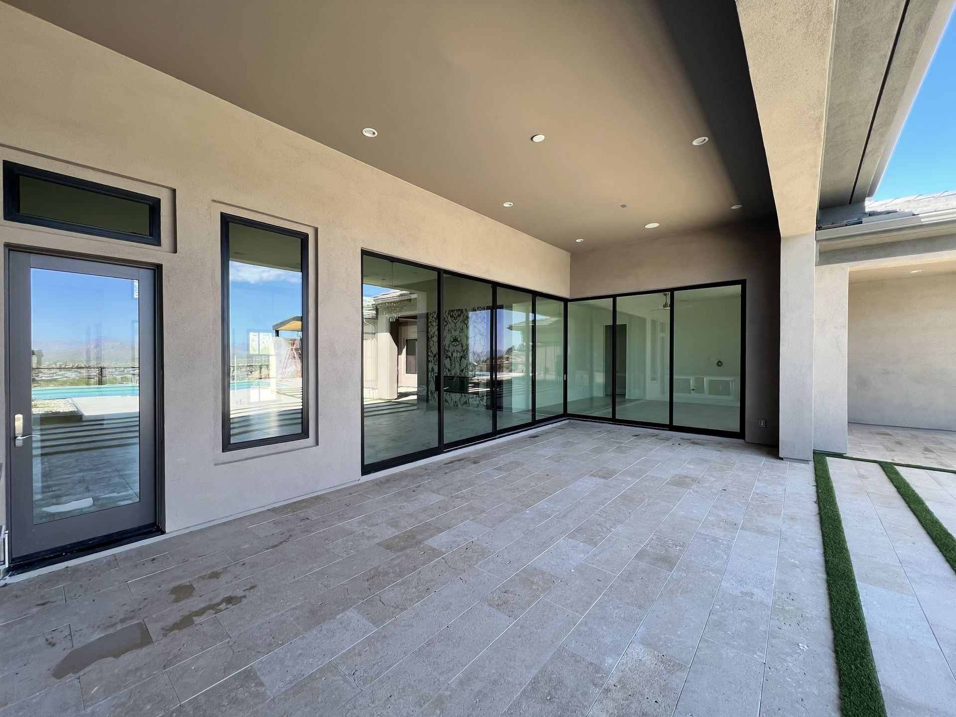 Covered patio with large glass doors, light stone floor, and a view of the water.