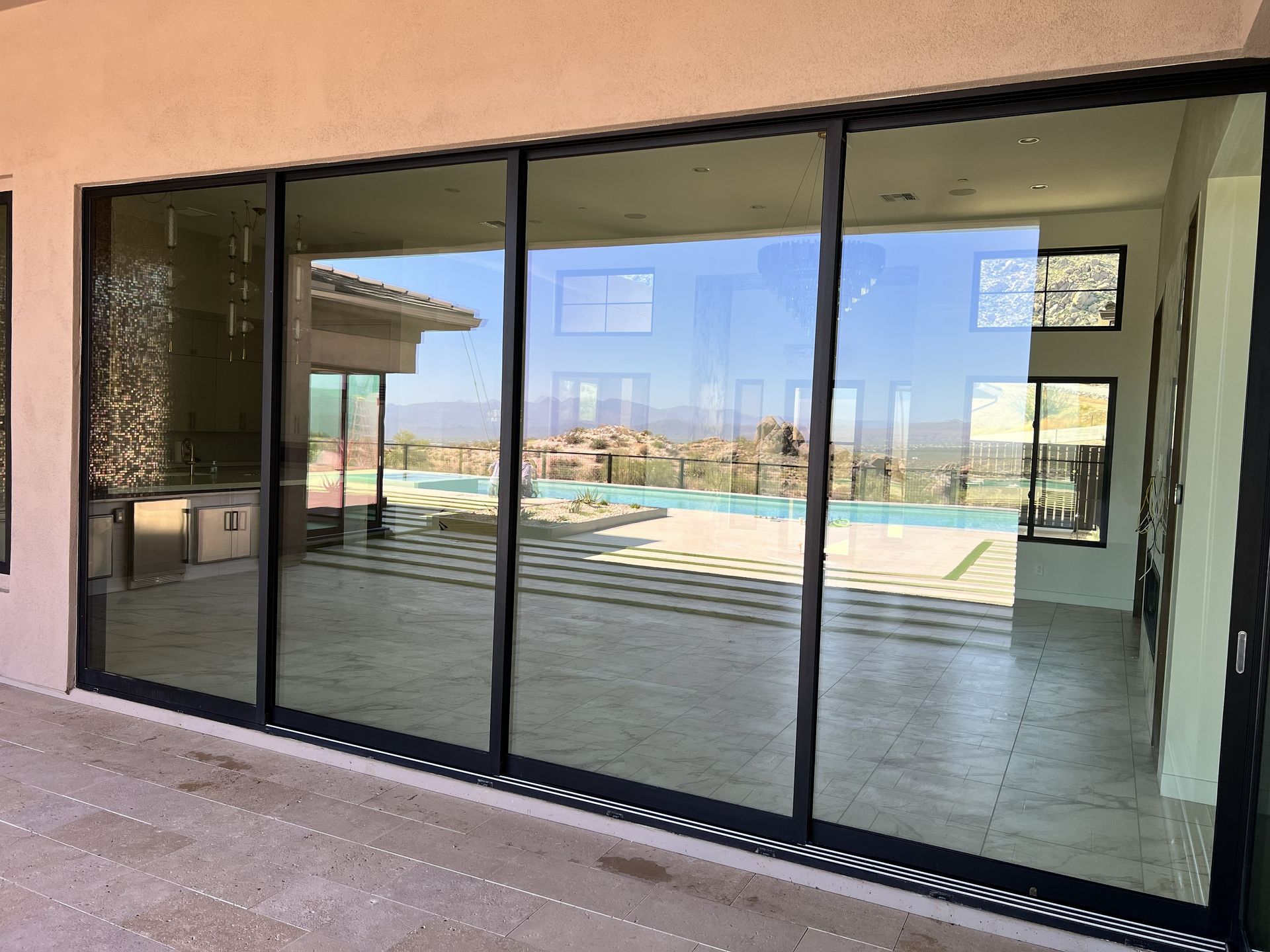 Sliding glass doors opening to a patio and swimming pool with mountain views.