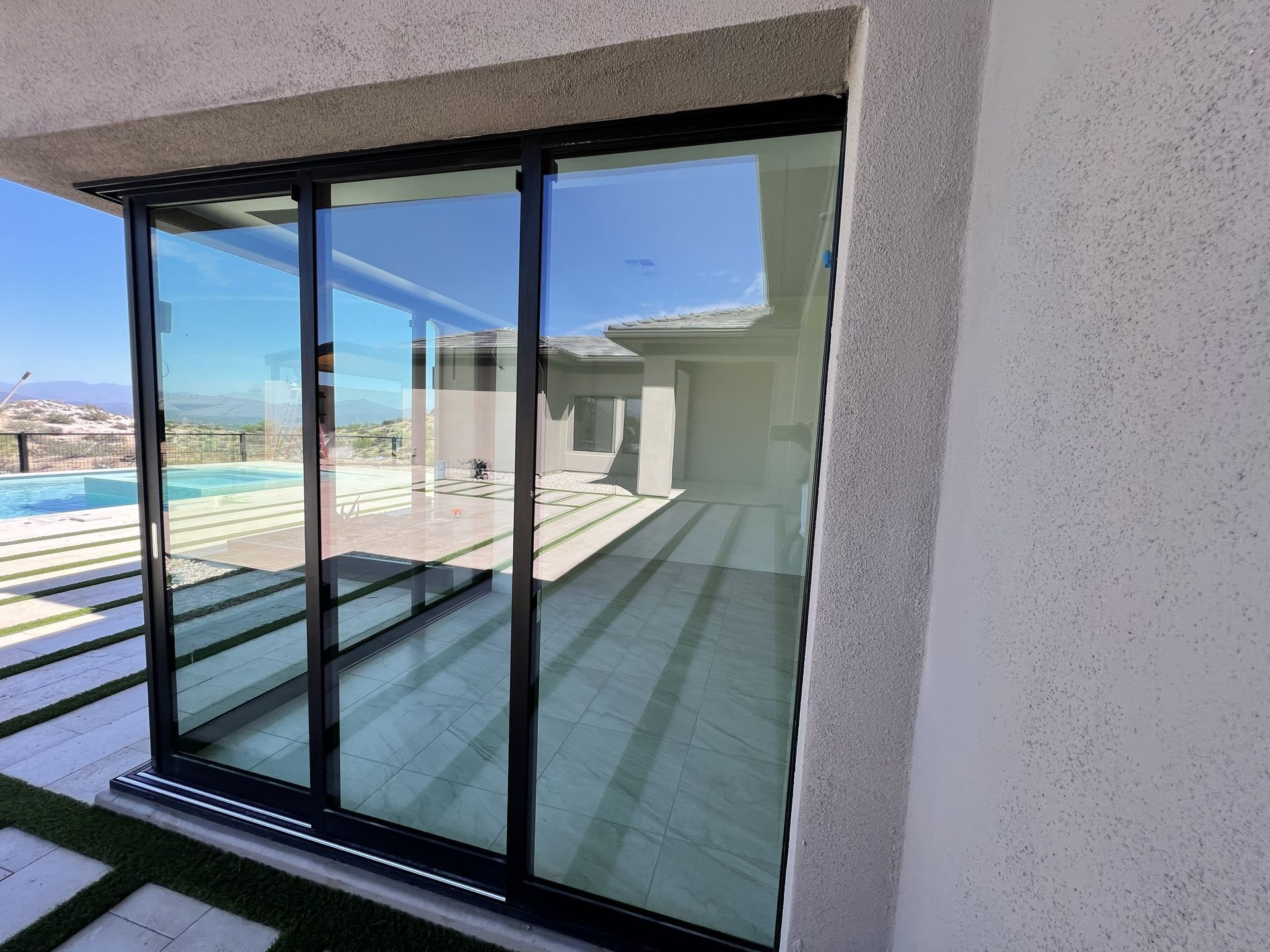 Sliding glass doors opening to a balcony with a pool and mountain view