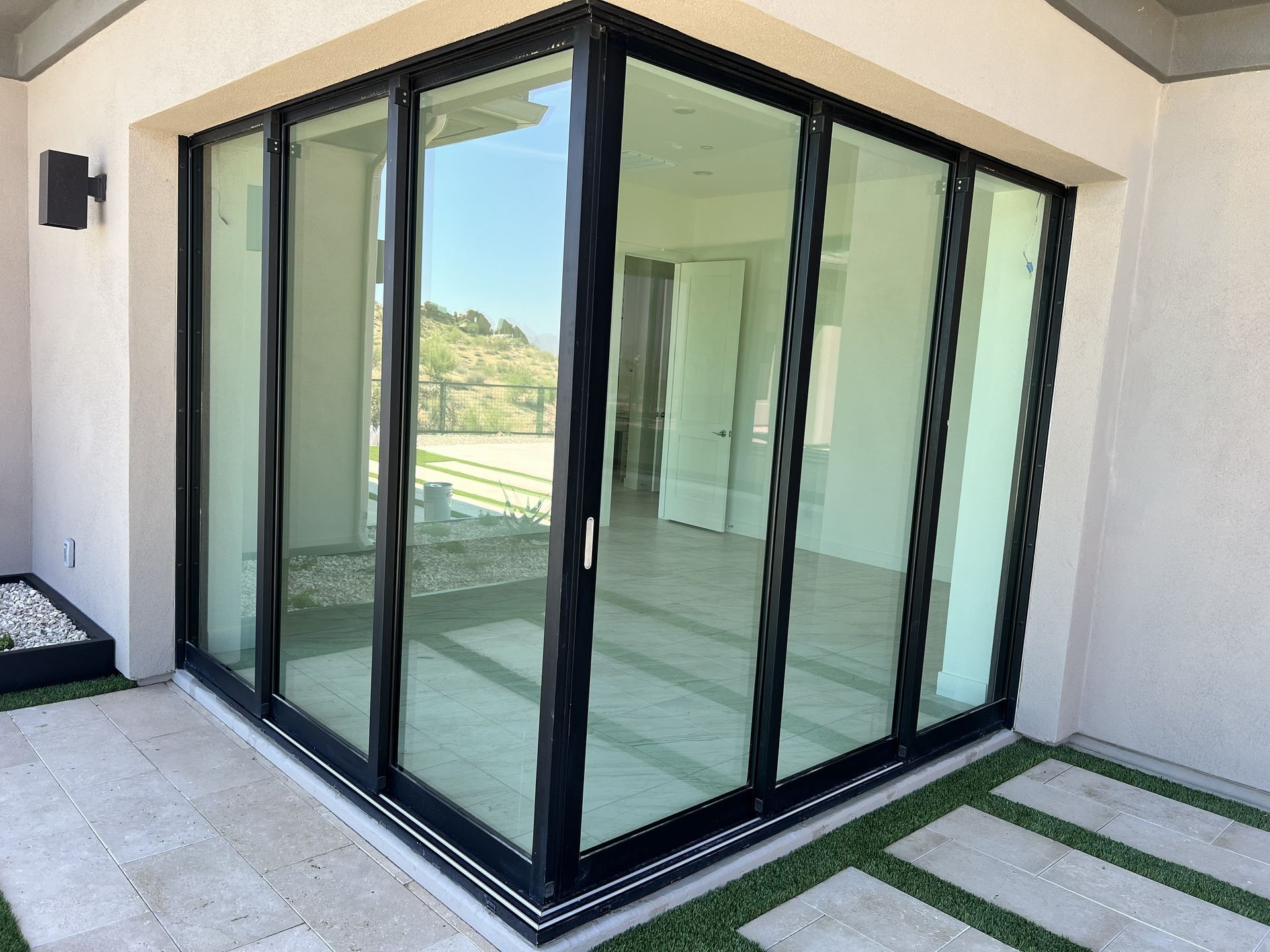 Corner glass patio enclosure with black frames and sliding doors on a tiled patio