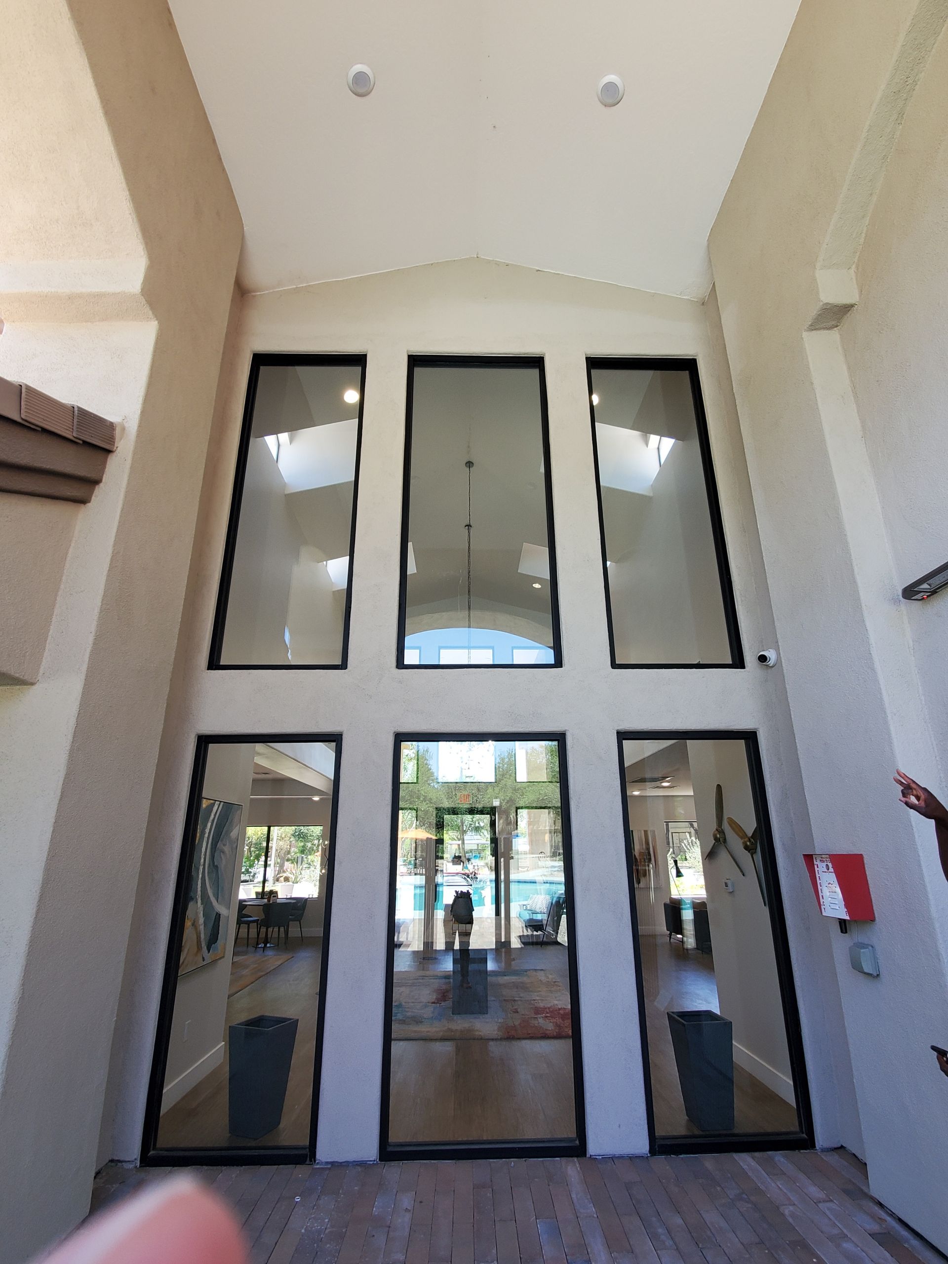 Glass double doors at a building entrance with white walls and tall windows above