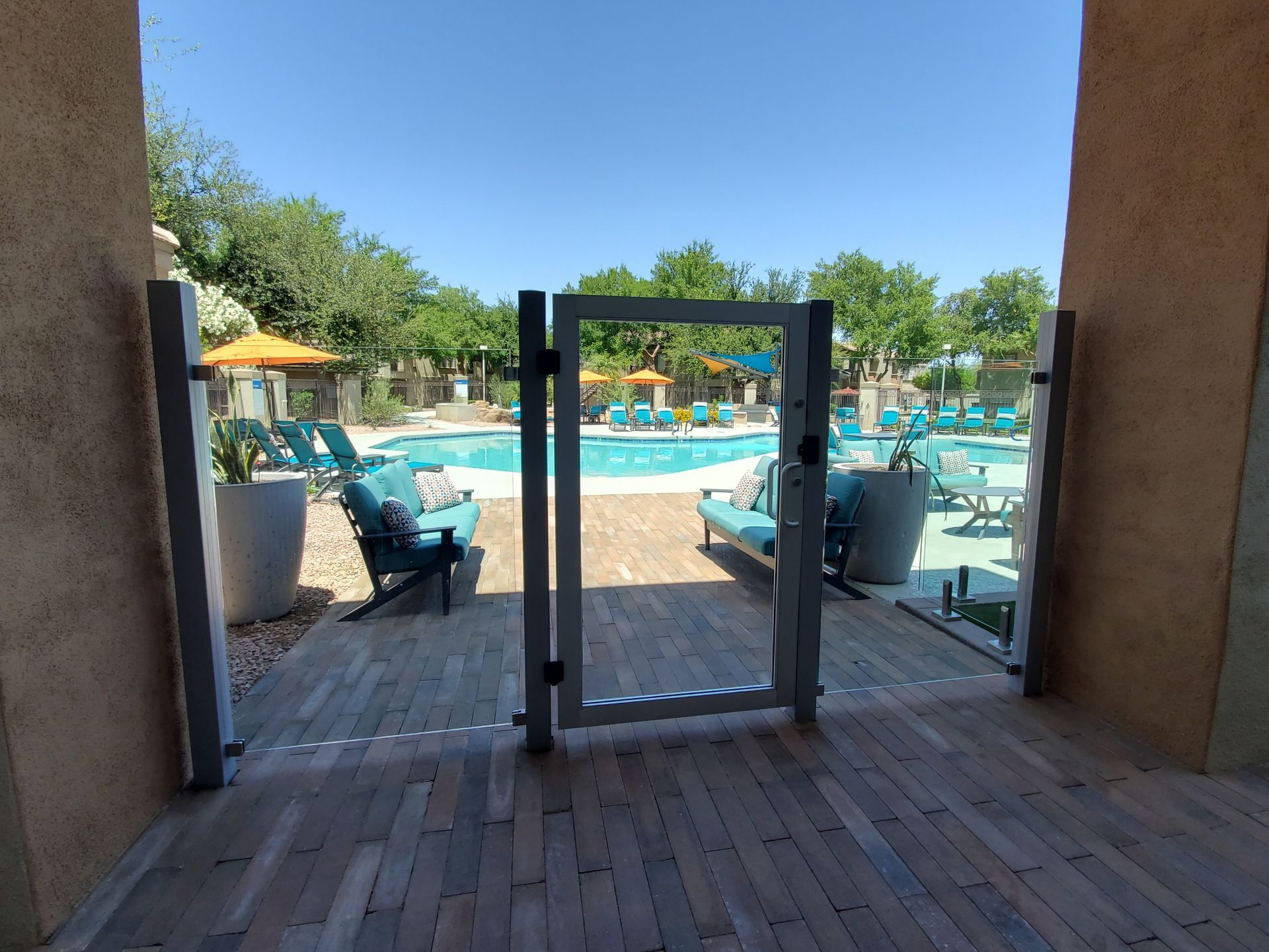 Pool area viewed through a doorway, with lounge chairs and umbrellas beside blue water.