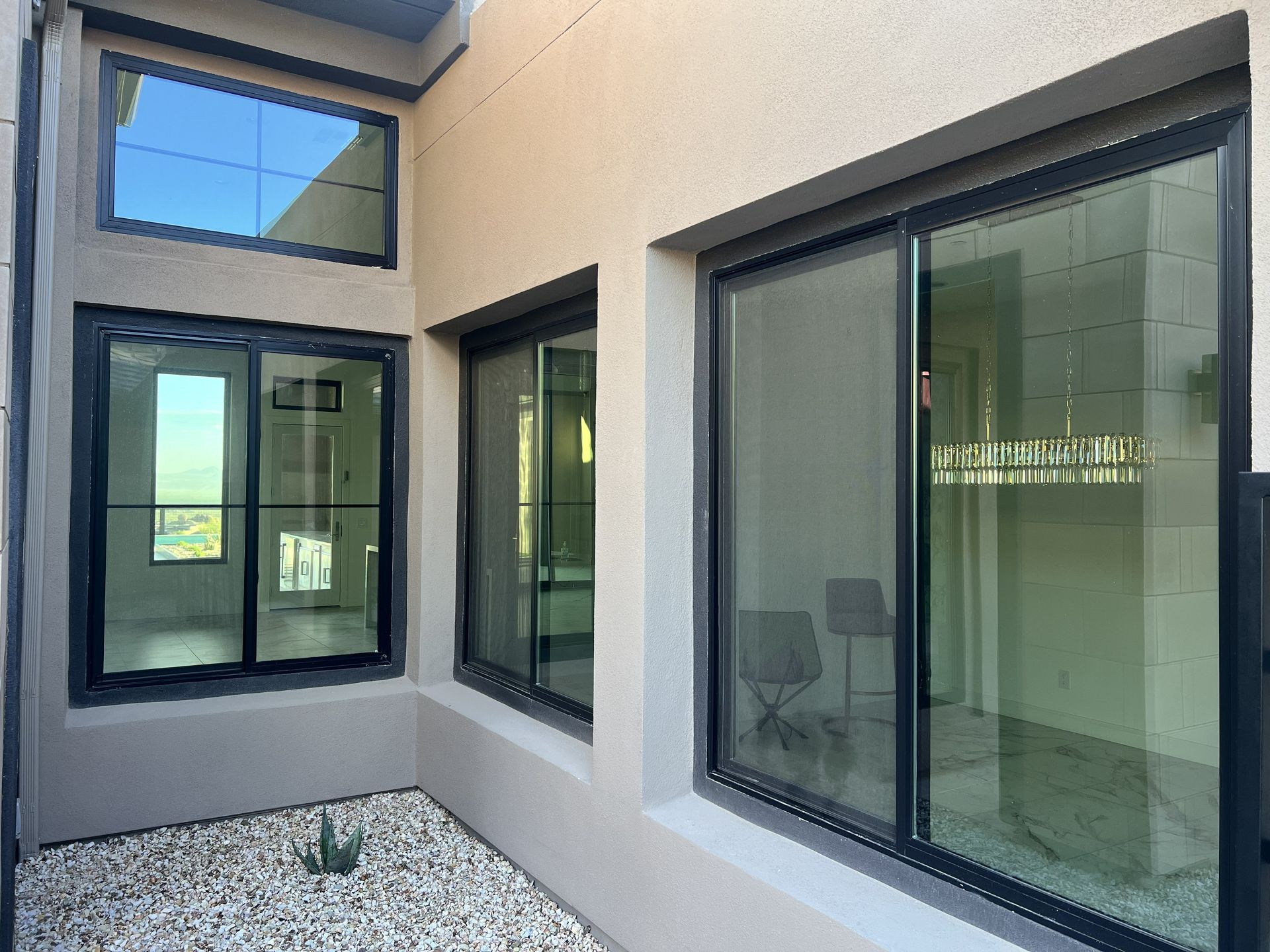 Modern apartment courtyard with gray walls, black-framed windows, and white gravel flooring