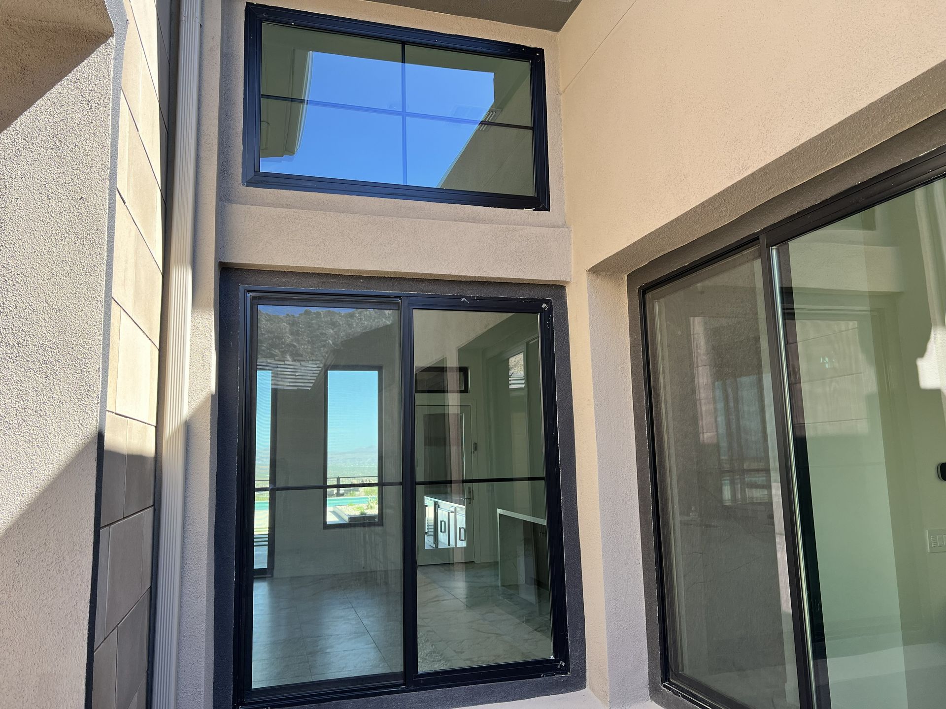 Exterior courtyard with modern windows and sliding glass doors beneath a blue-tinted transom window