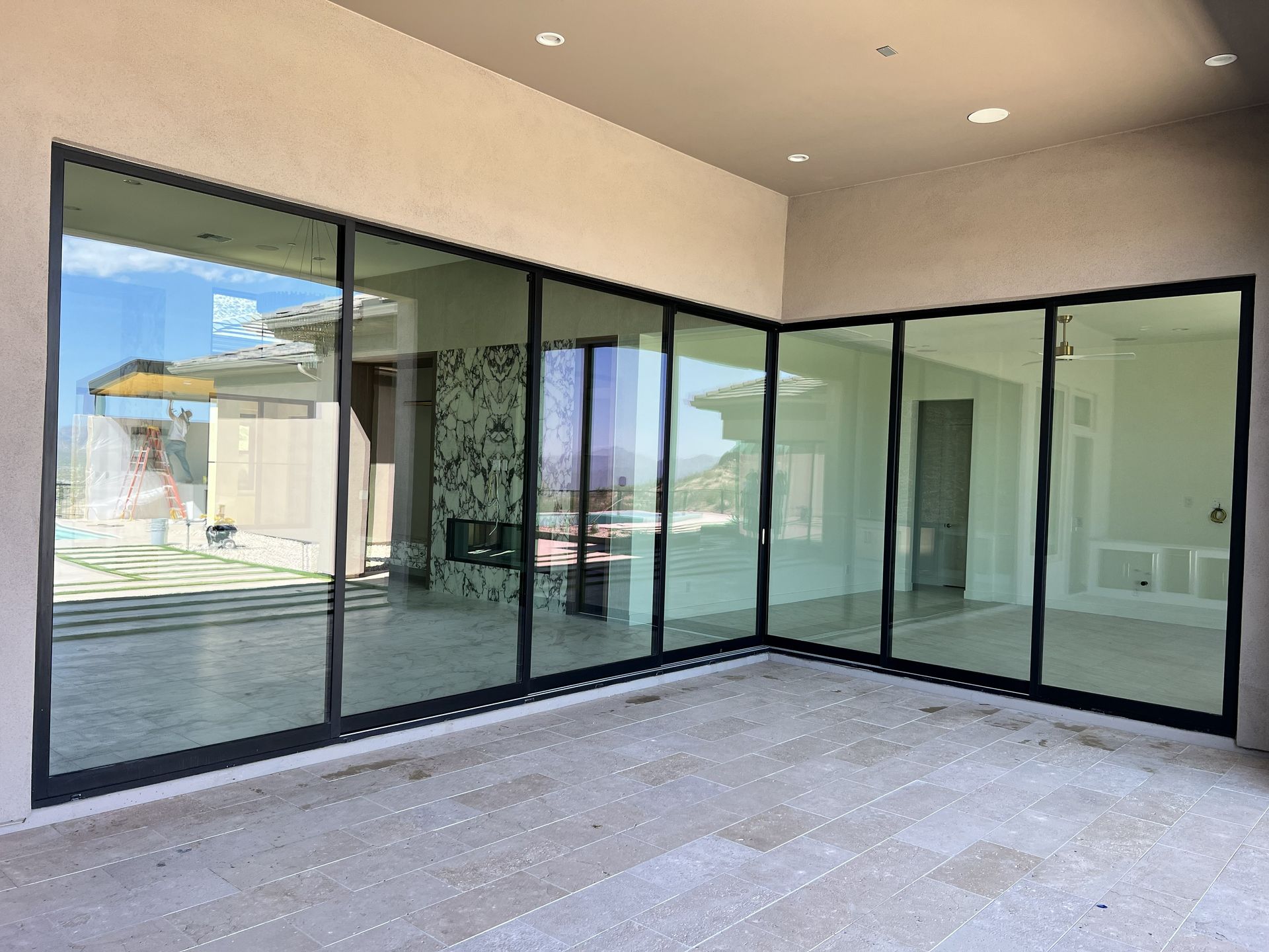 Empty covered patio with large black-framed glass sliding doors and beige walls