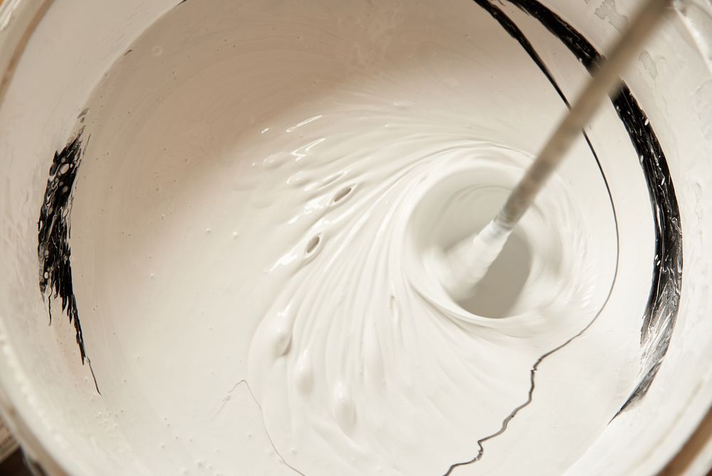 A Bucket Of White Paint Is Being Stirred With A Mixer — Mid Coast Coatings In Kempsey, NSW