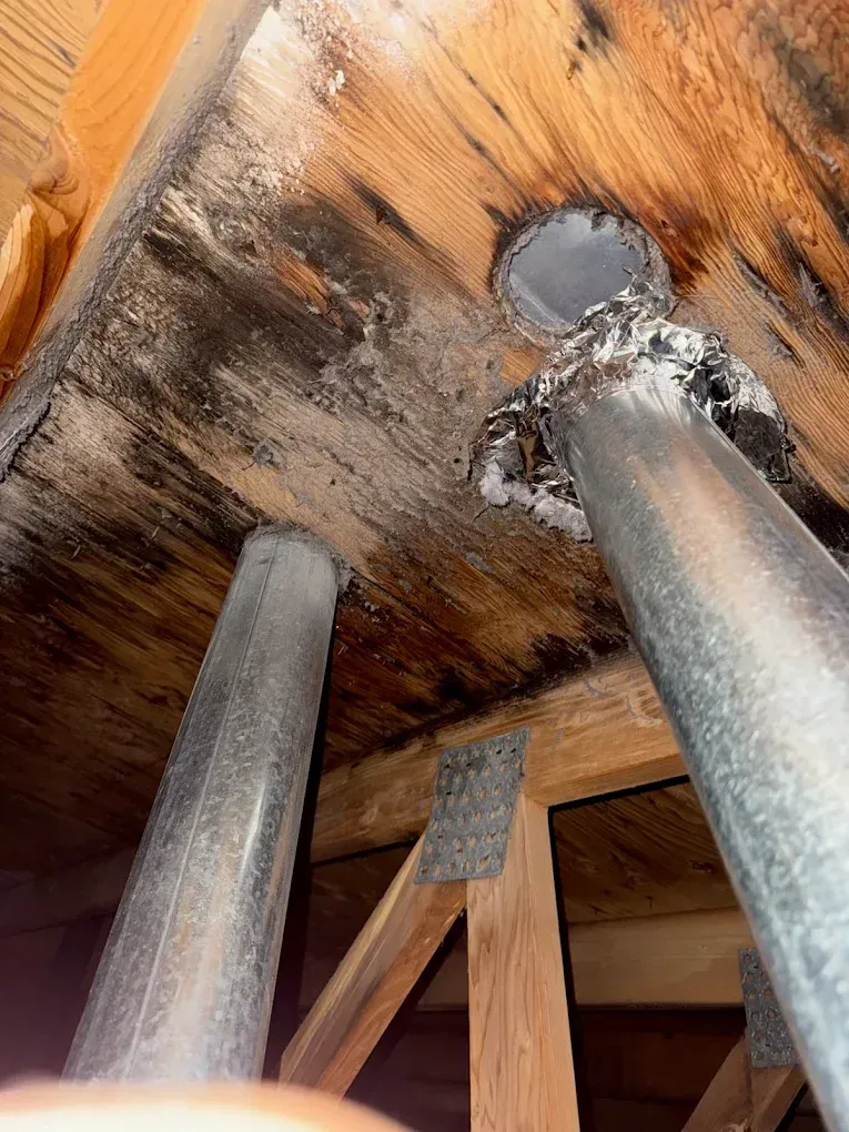 Close-up of wooden furniture underside with three metal legs and a central bolt against a warm wood grain surface