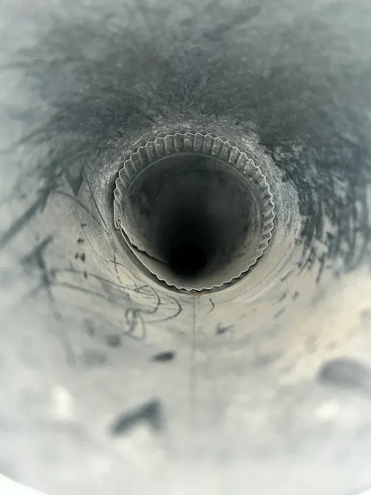View down a gray cylindrical pipe with a dark circular opening and textured inner walls