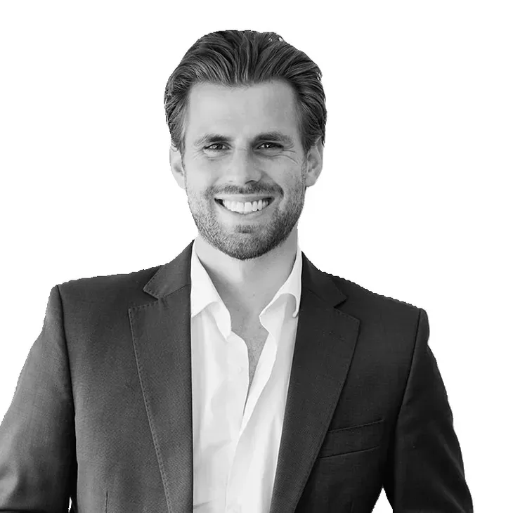 Man in a suit smiling; black and white.