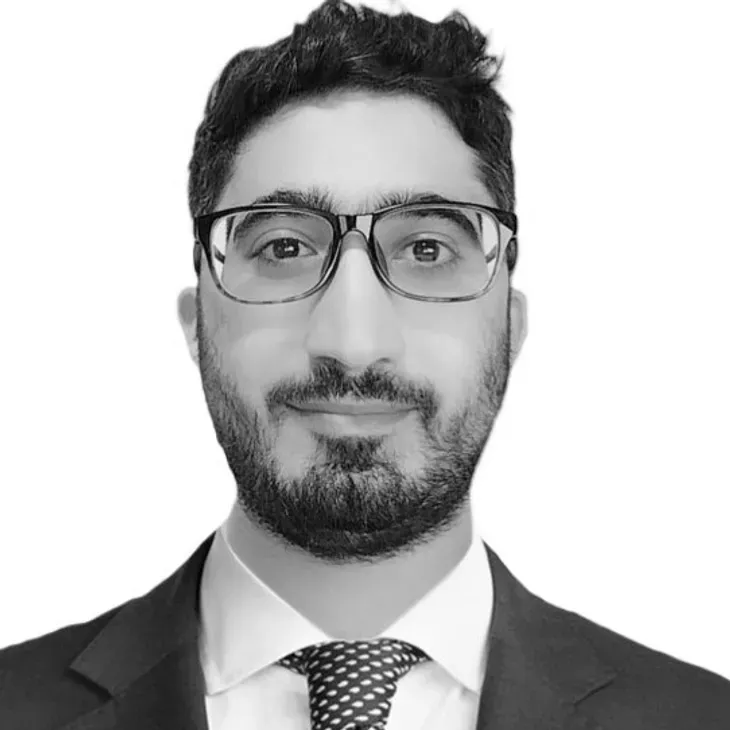 Man with glasses and beard in a suit, looking at the camera.