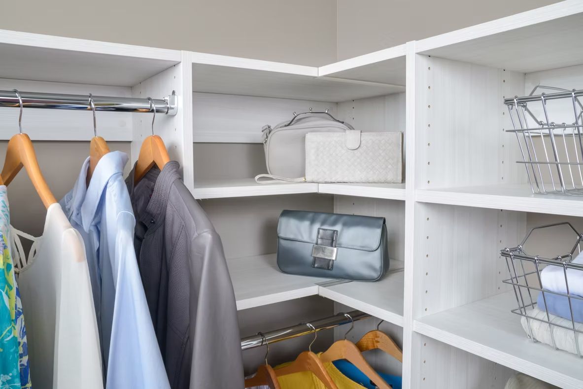 Walk-in closet with hanging shirts, folded towels, and storage baskets on white shelves
