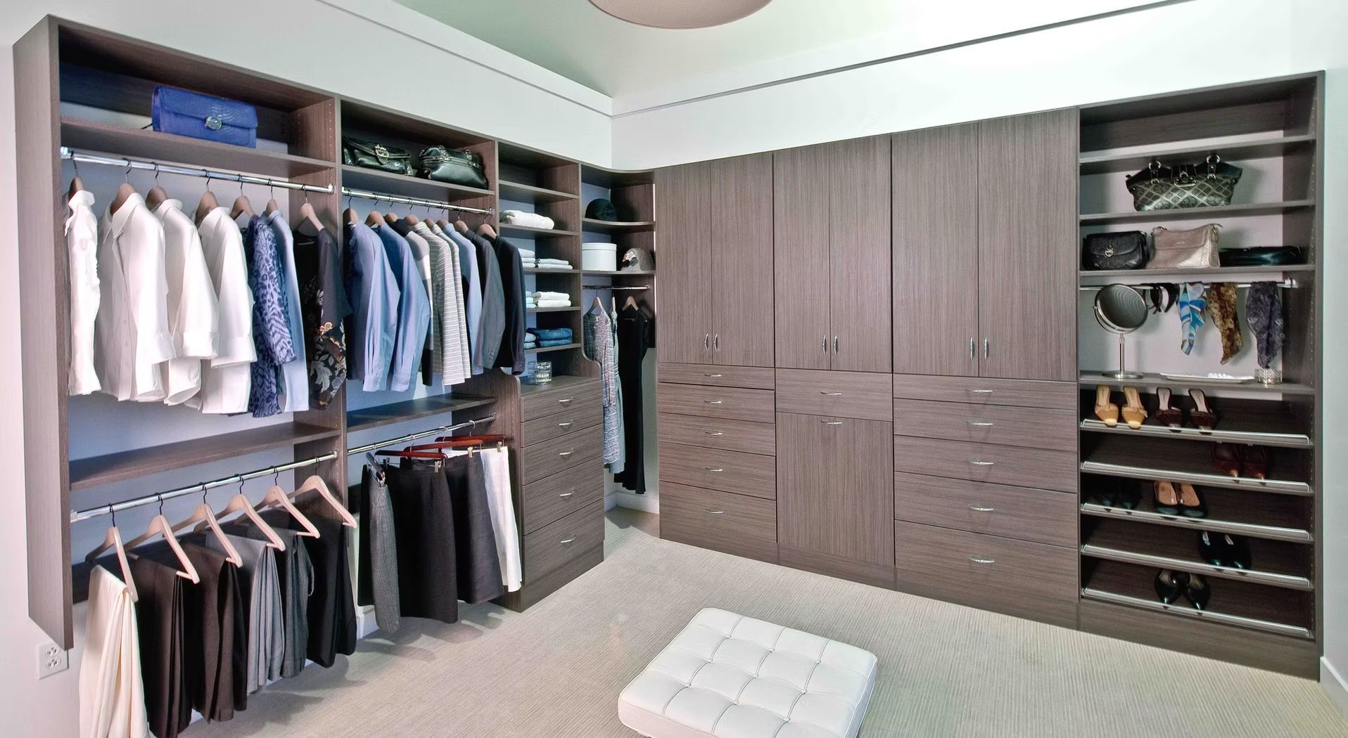 Spacious walk-in closet with hanging clothes, drawers, shelves, and built-in shoe storage in a modern gray room