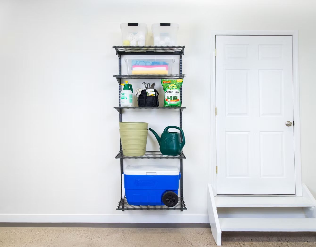Wall-mounted shelving with storage bins and cleaning supplies beside a closed white door