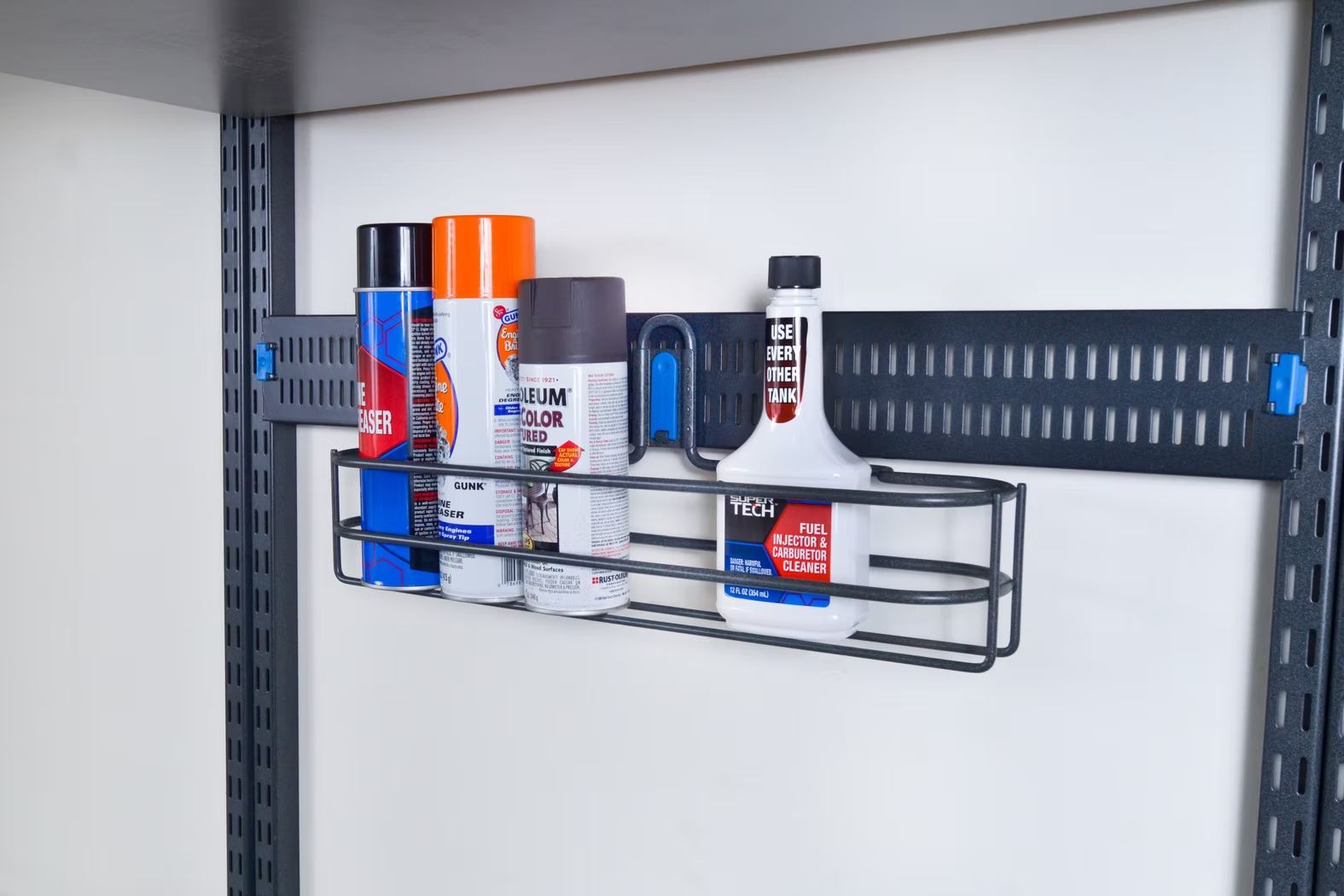 Wall-mounted wire shelf holding assorted spray cans and bottles in a garage or storage area