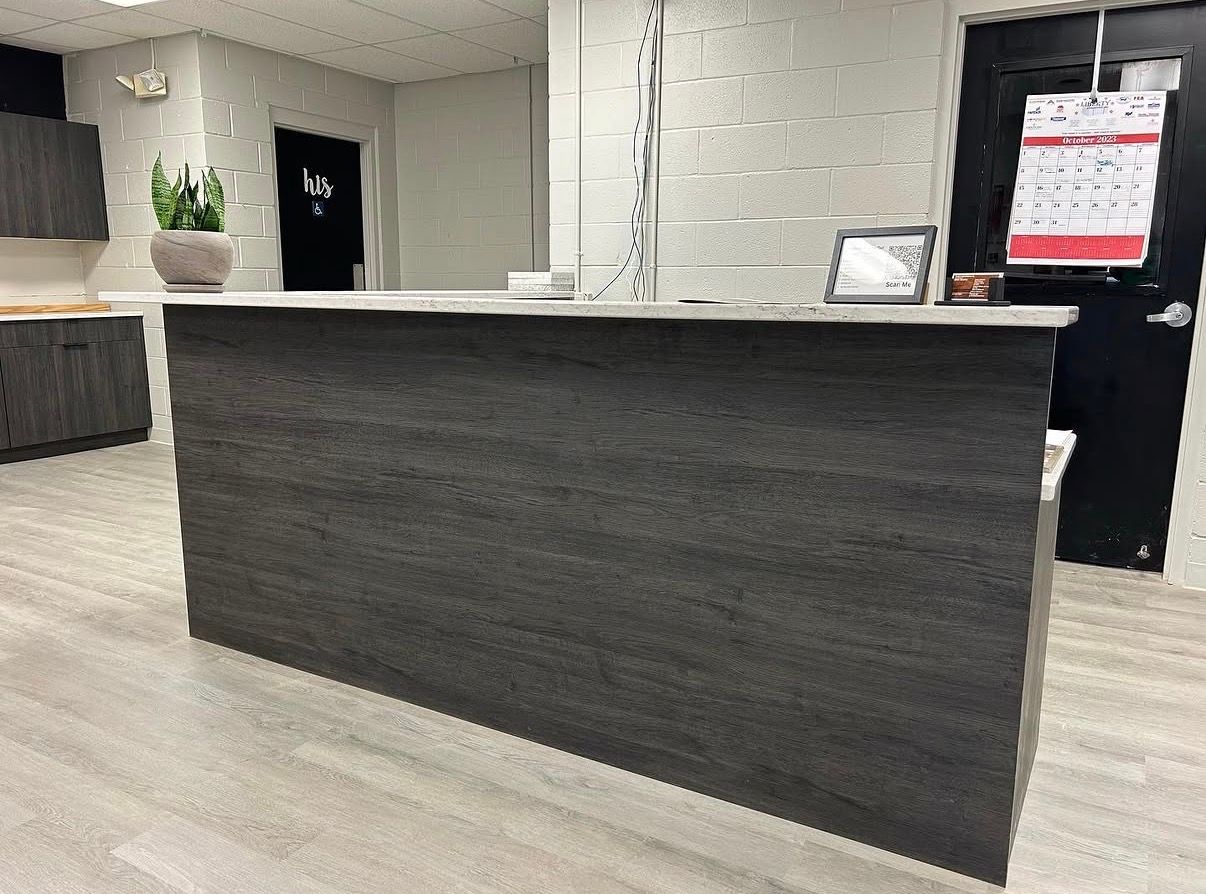 Empty office reception area with a dark wood front desk and white brick walls