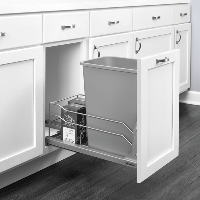 Pull-out kitchen cabinet organizer with bins and a trash bin under the sink.