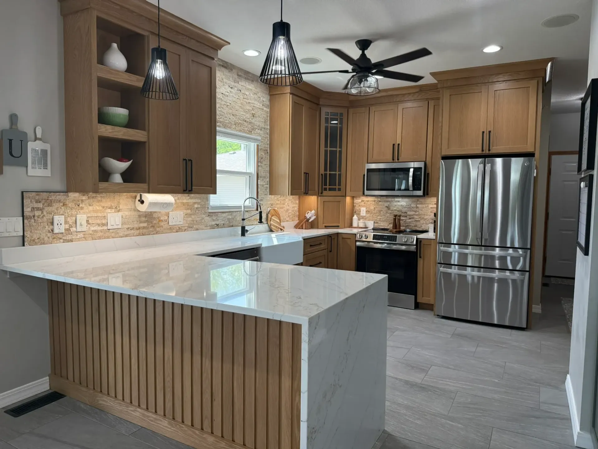 Modern kitchen with granite island, wooden cabinets, stainless appliances, and ceiling fan