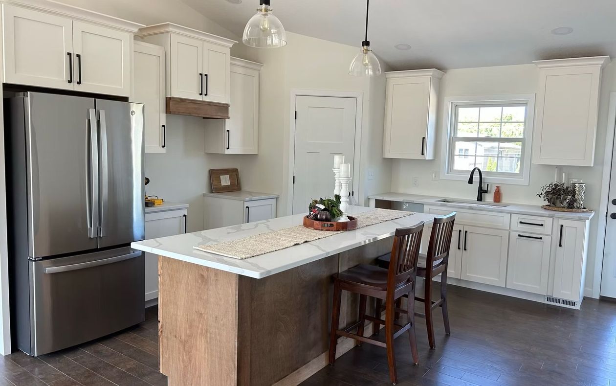 Bright white kitchen with stainless fridge, island, bar stools, and pendant lights