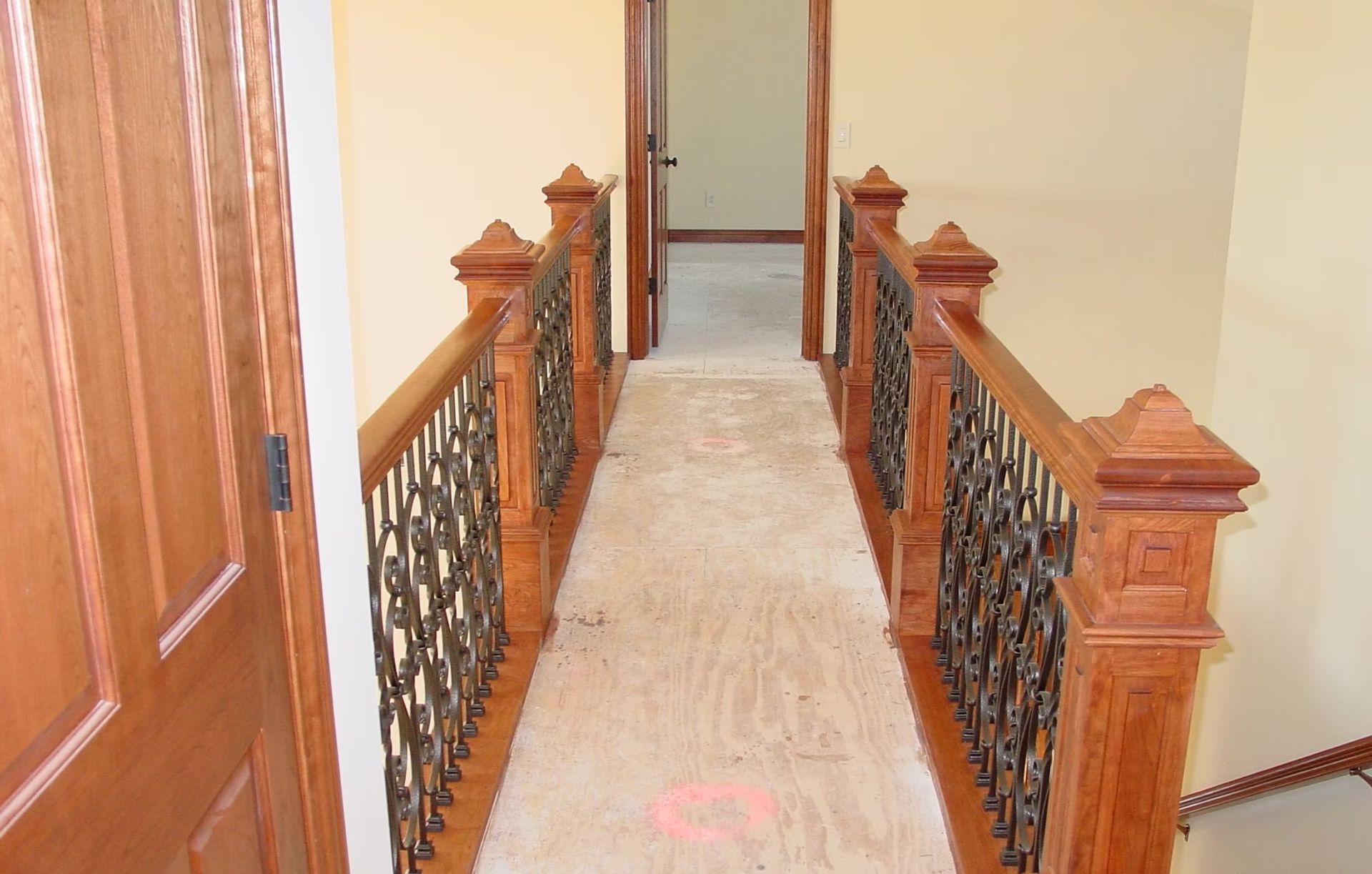 Narrow indoor hallway with ornate wooden railings and a carpeted floor leading to a doorway