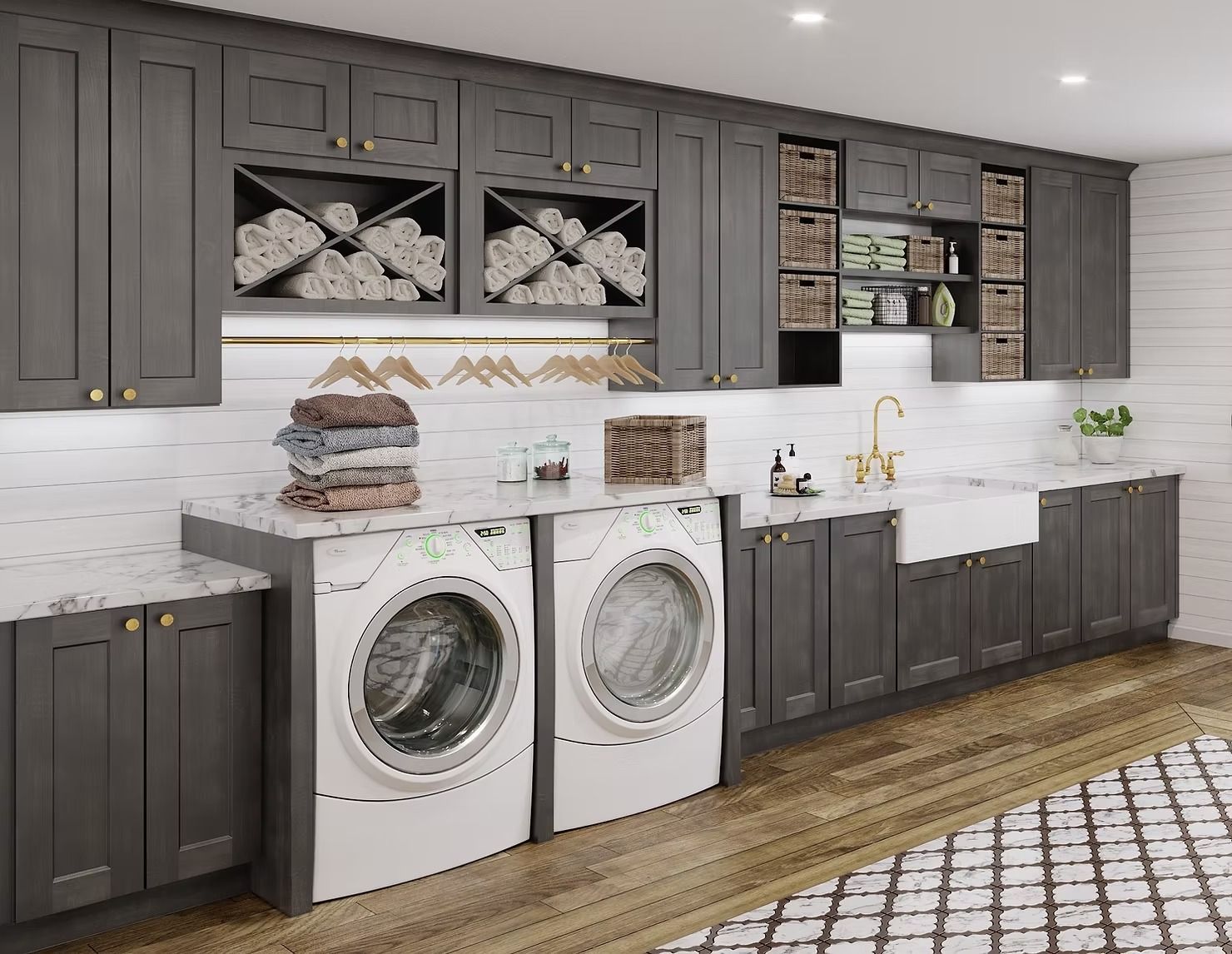 Modern laundry room with dark cabinets, white countertops, front-load washer and dryer, and wood flooring
