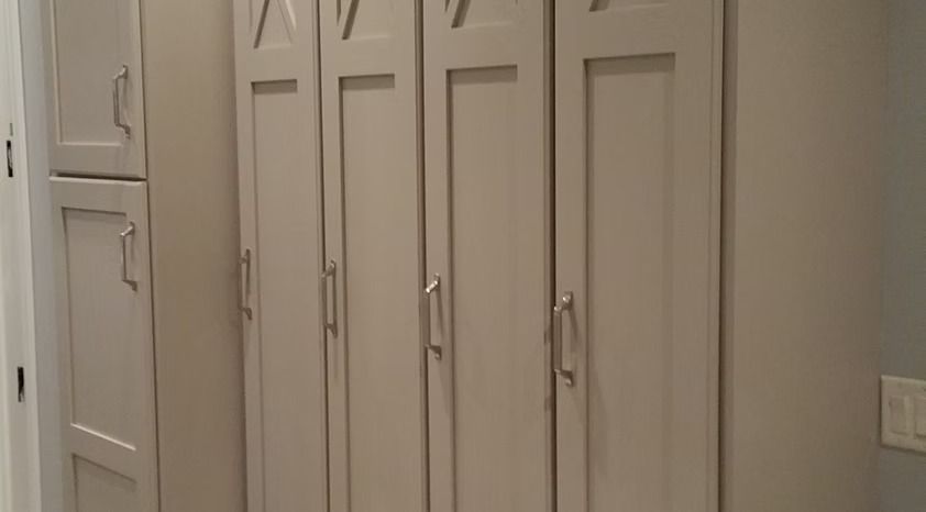 White kitchen cabinets and a pantry door along a beige wall.