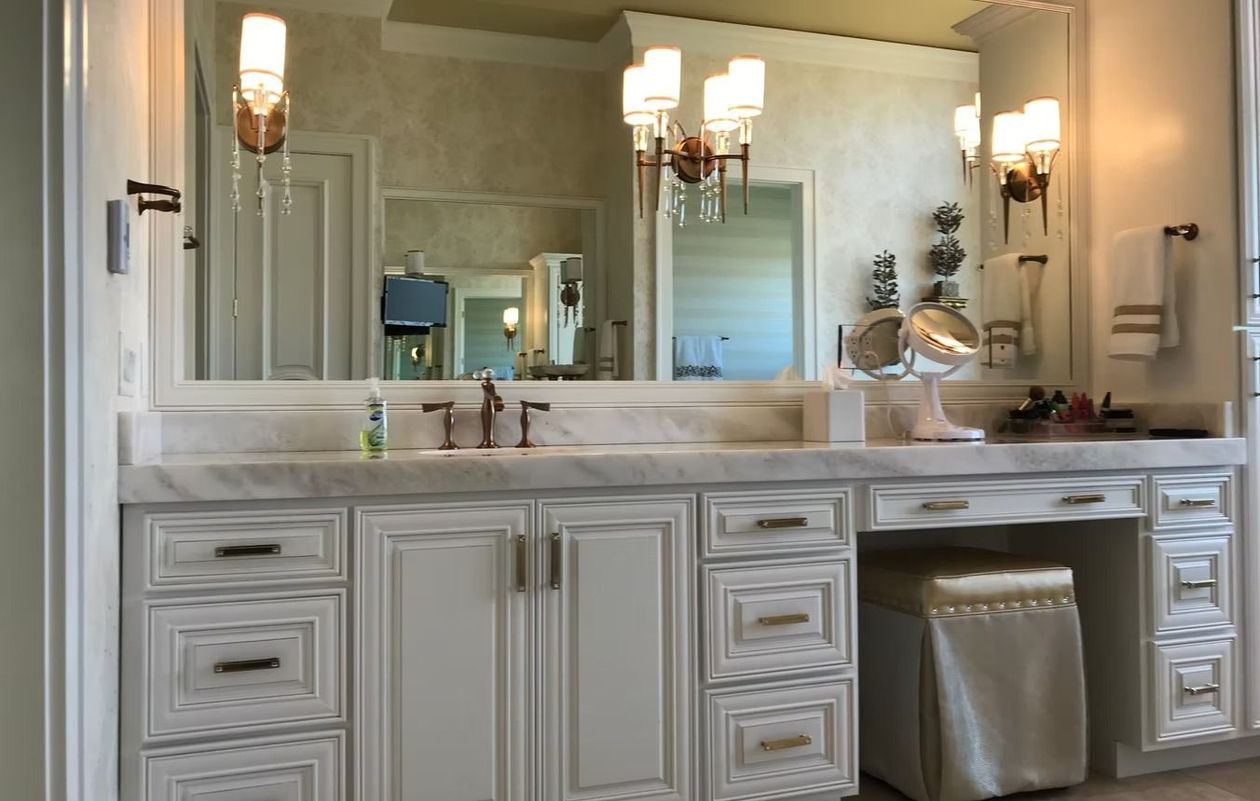 Luxurious bathroom vanity with double sinks, mirrors, wall sconces, and a silver trash bin
