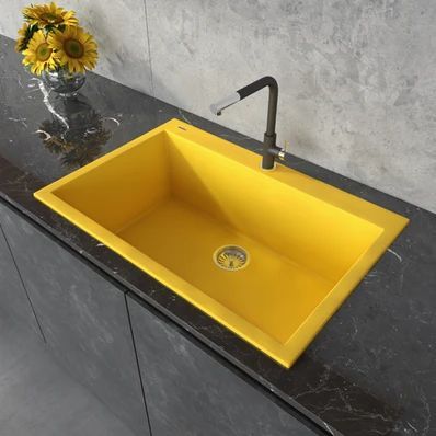 Yellow rectangular sink with black countertop and faucet, with a vase of sunflowers nearby.