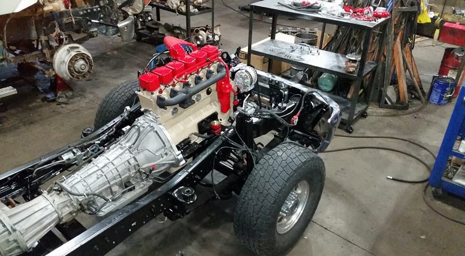 Partially assembled black hot rod with exposed engine in a garage workshop