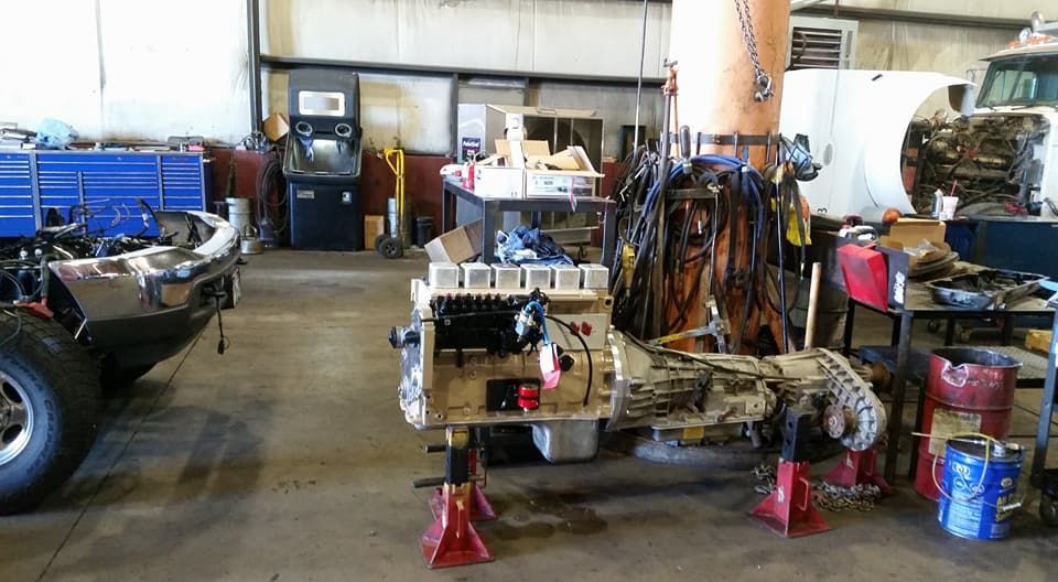 Auto repair shop with a vehicle chassis on red jack stands and tools scattered around the garage