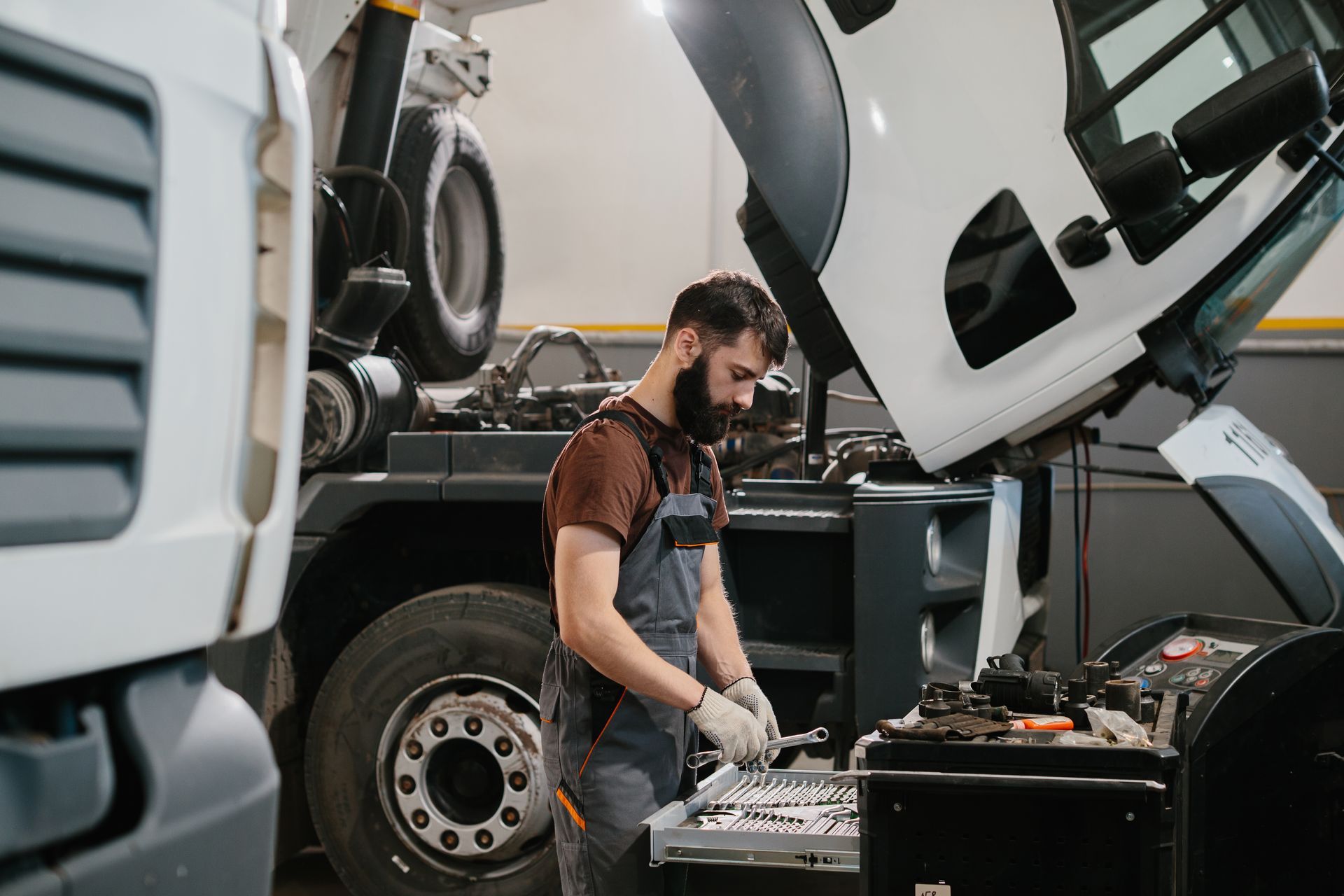 Truck technician performing maintenance and diagnostics on a commercial vehicle in a service bay.