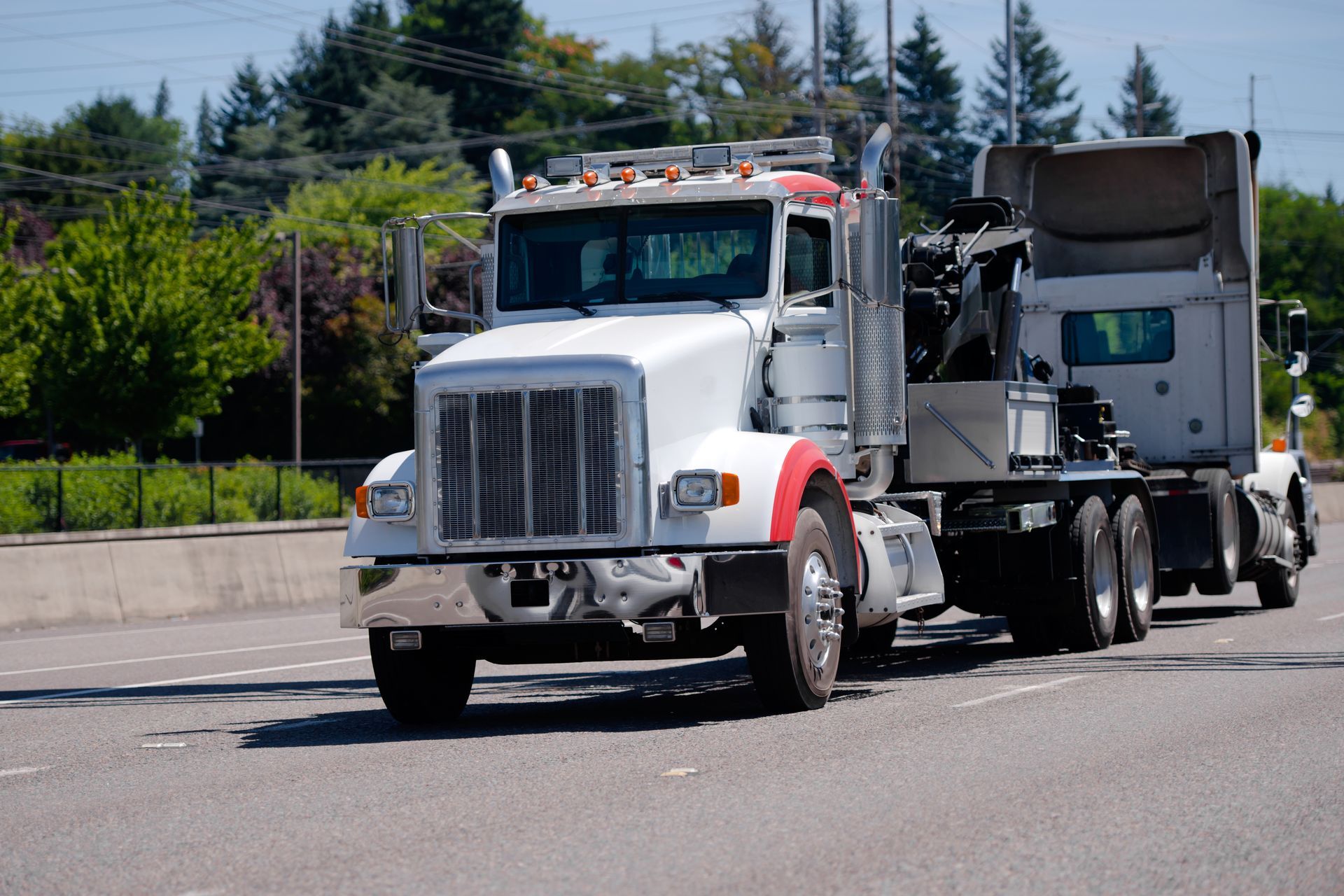 White dump truck towing a gray trailer on a road under a clear sky