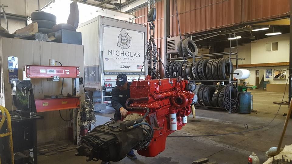 Red engine block in an auto repair shop beside stacked tires and a vehicle lift