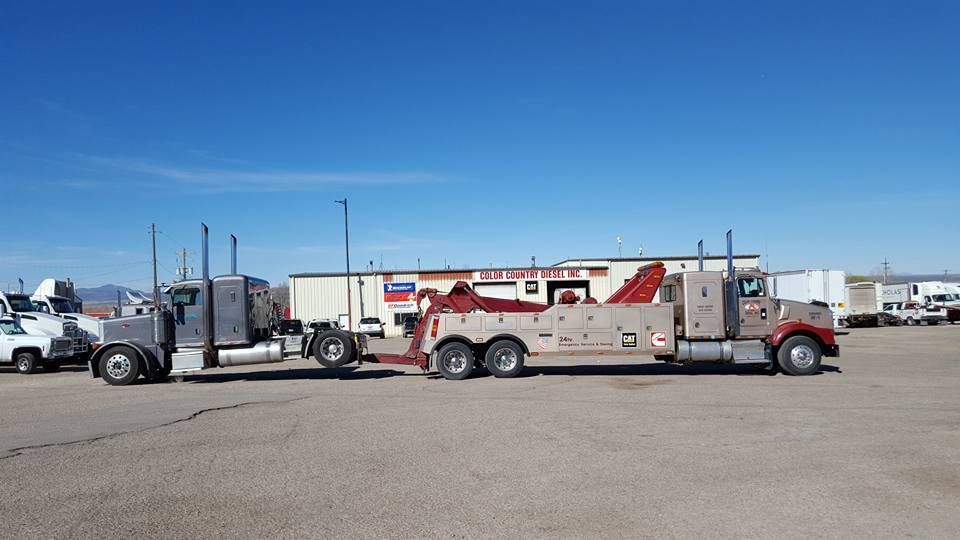 Red and white utility truck parked in a lot with trailers and equipment under a clear blue sky