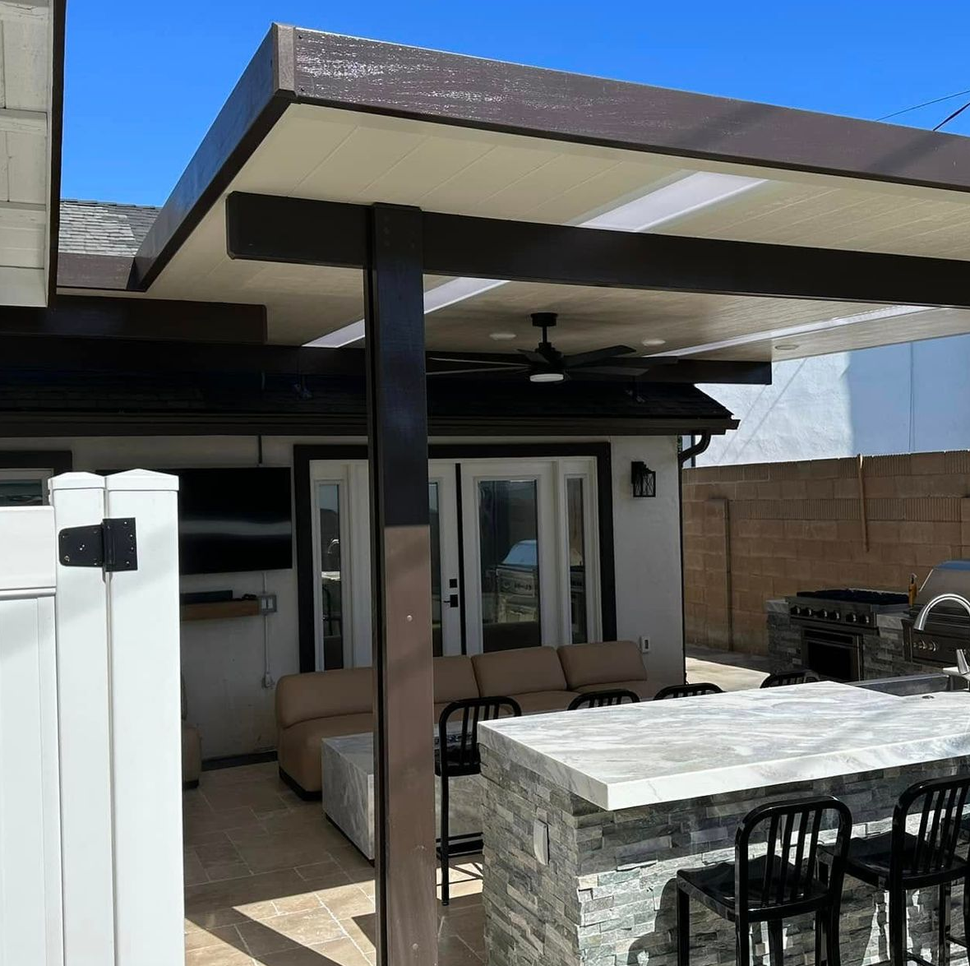 Patio with beige seating, stone table, and modern black-post pergola under a clear blue sky