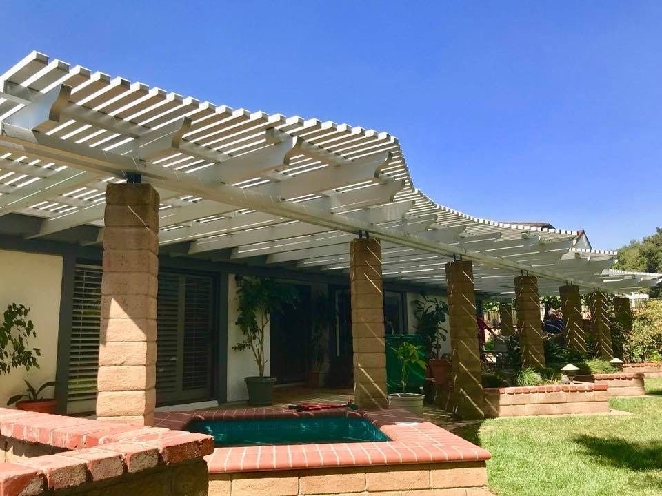 Patio with white pergola, brick columns, and a small turquoise pool under a clear blue sky