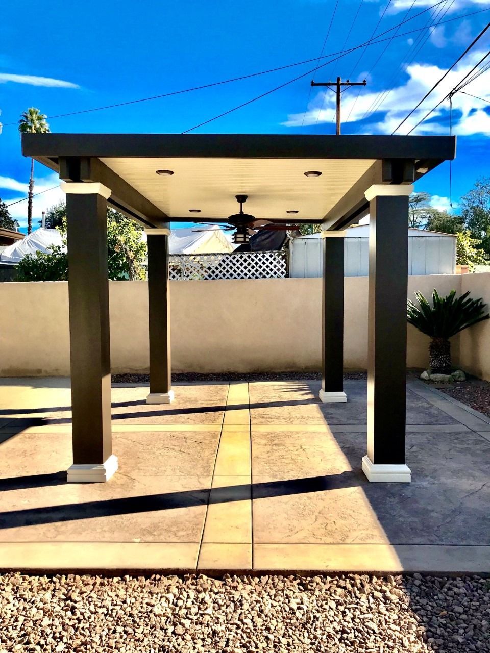 Modern outdoor pergola with four columns on a sunlit patio under a blue sky