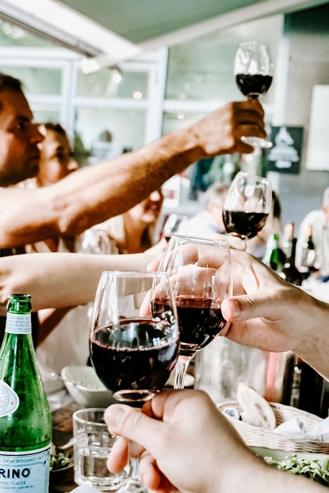 People toasting with red wine glasses outdoors.