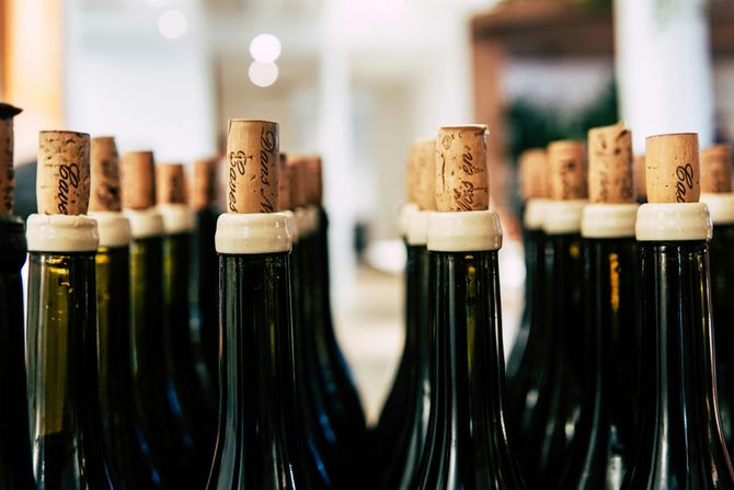 Rows of dark green wine bottles with cork stoppers.