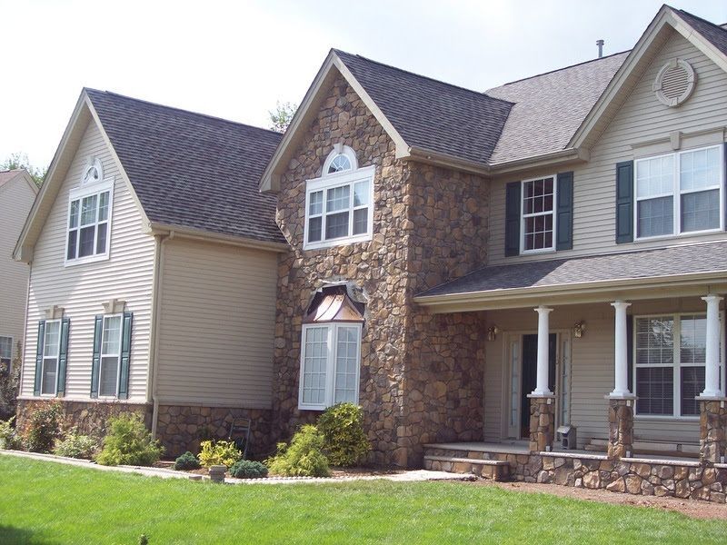 Large suburban house with stone and beige siding, white trim, and a front porch.