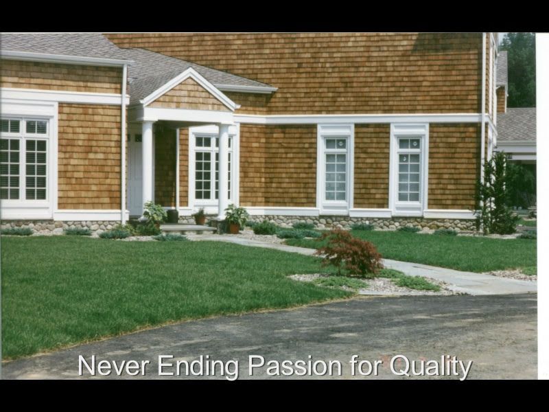 Suburban house exterior with brown siding, white trim, front lawn, and walkway, captioned “Never Ending Passion for Quality”