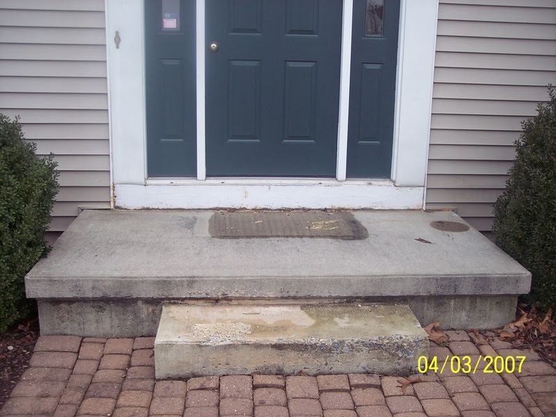 Front porch with concrete steps leading to a dark blue front door and sidelights.