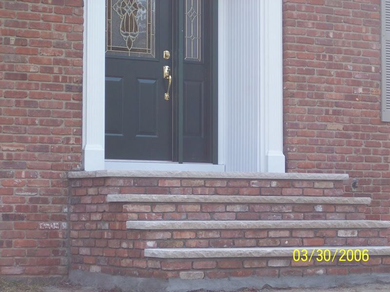 Brick house front steps leading to a black front door with white trim