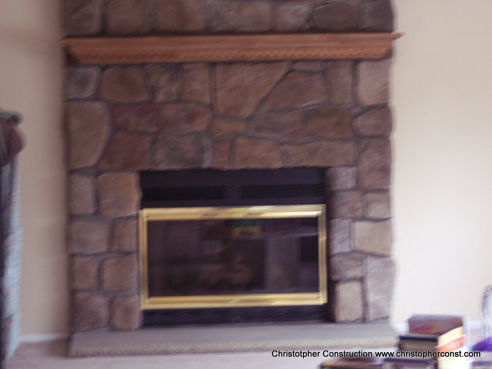 Stone fireplace with a brass-trimmed glass hearth insert in a living room