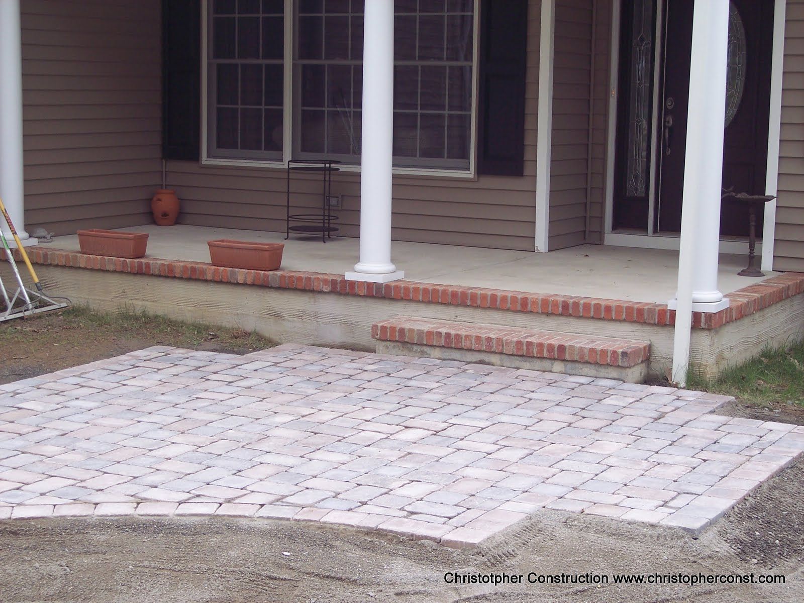 Brick patio and porch steps with white columns in front of a house