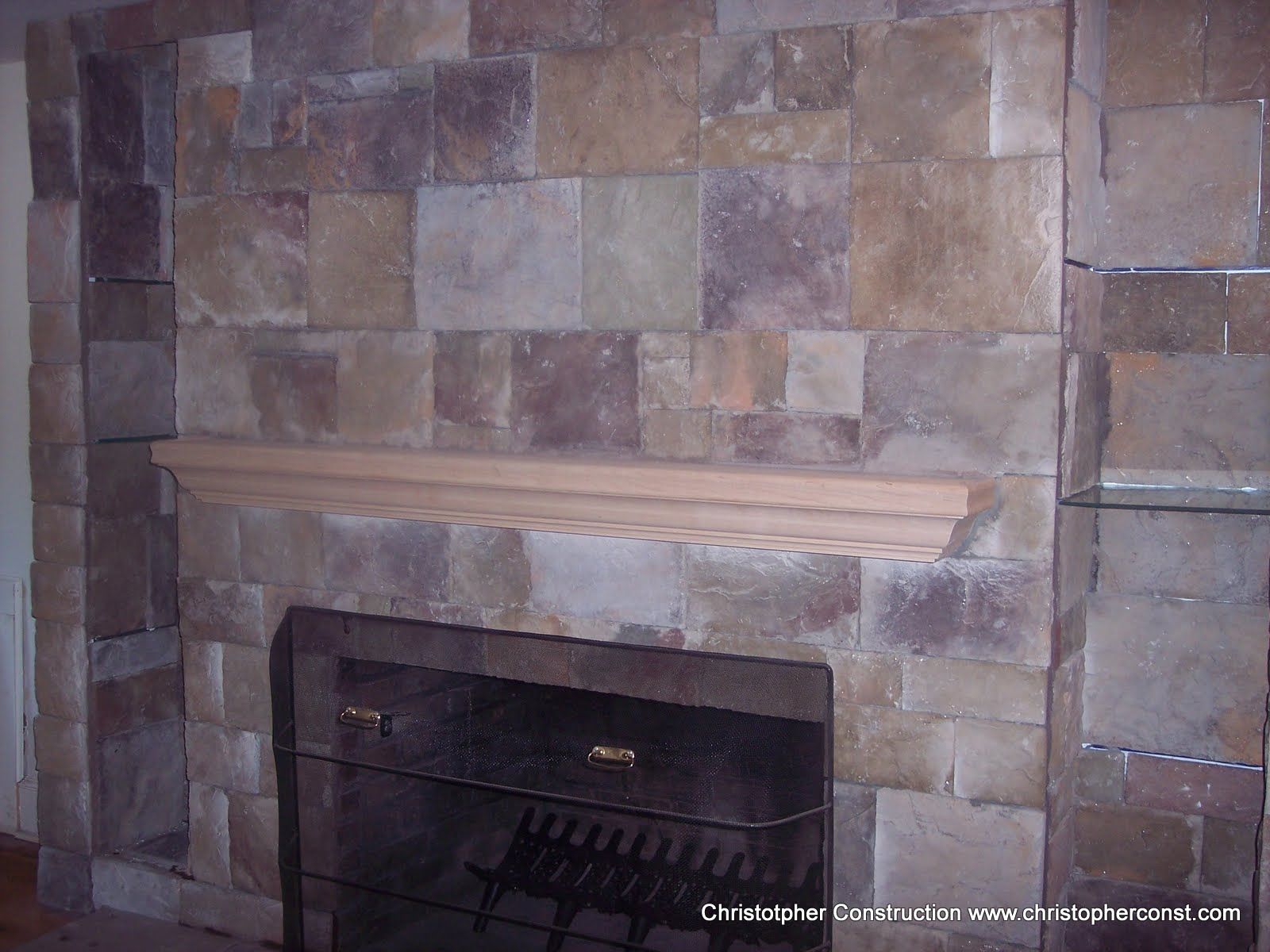 Stone fireplace with a wooden mantel and a dark firebox surround.