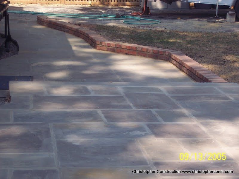 Stone walkway beside a brick-edged garden path in a sunlit outdoor area