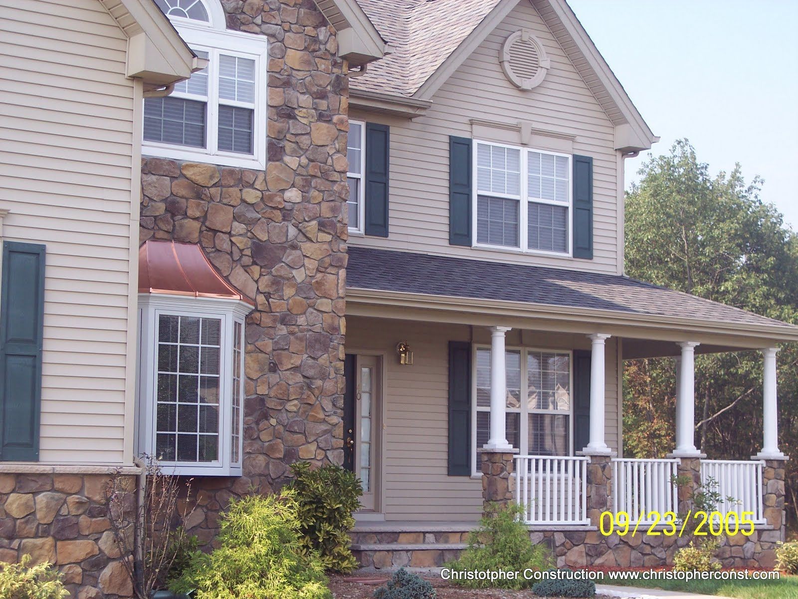Two-story suburban house with stone facade, porch, shutters, and white columns