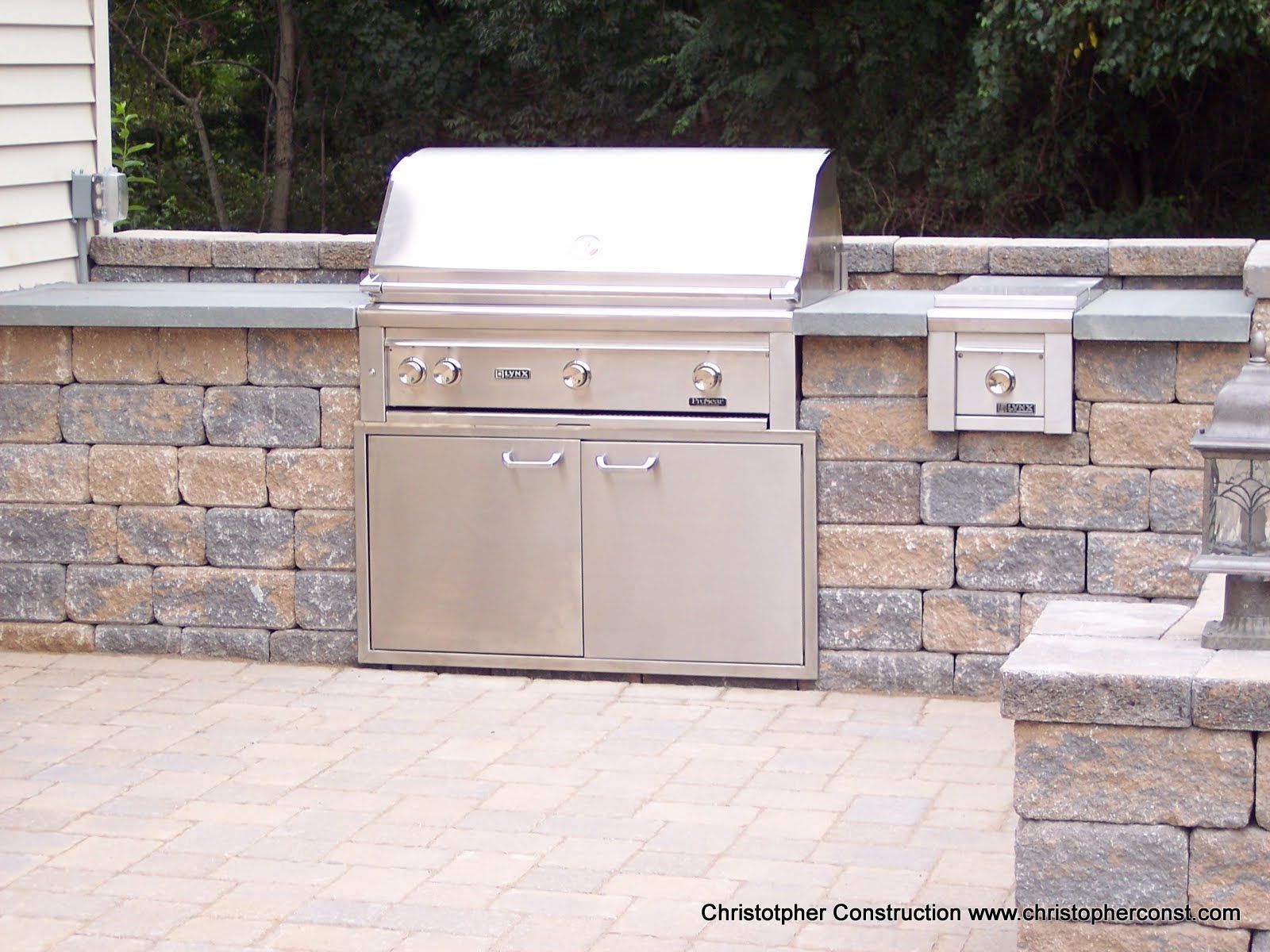 Built-in stainless steel grill and side burner set into a stone outdoor patio wall