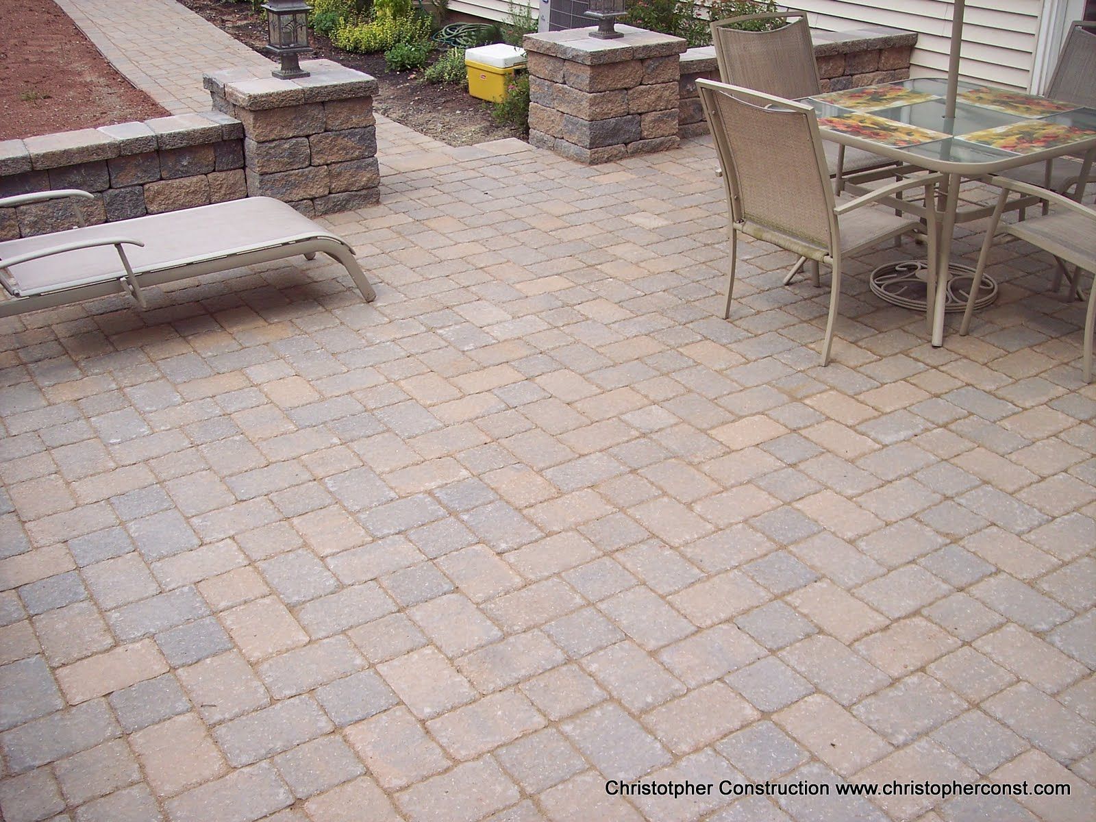 Patio with brick pavers, a lounge chair, and a glass-top table with chairs.